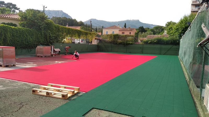Image des travaux de pose des dalles du revêtement modulaire lors de la rénovation du court à l'étape 5