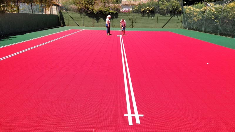 Image de la réalisation des lignes de jeu sur le revêtement modulaire lors de la rénovation du court à l'étape 6